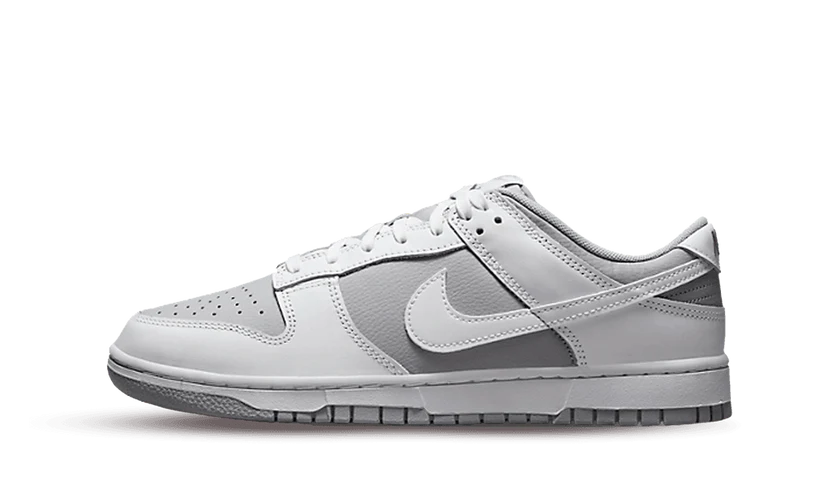 La Nike Dunk Low Retro White Grey presenta una base in pelle grigia con sovrapposizioni in pelle bianca, compreso lo Swoosh laterale. Questa combinazione classica è evidenziata anche sulla suola, mentre il ricamo argentato sul tallone aggiunge un tocco di eleganza al design.