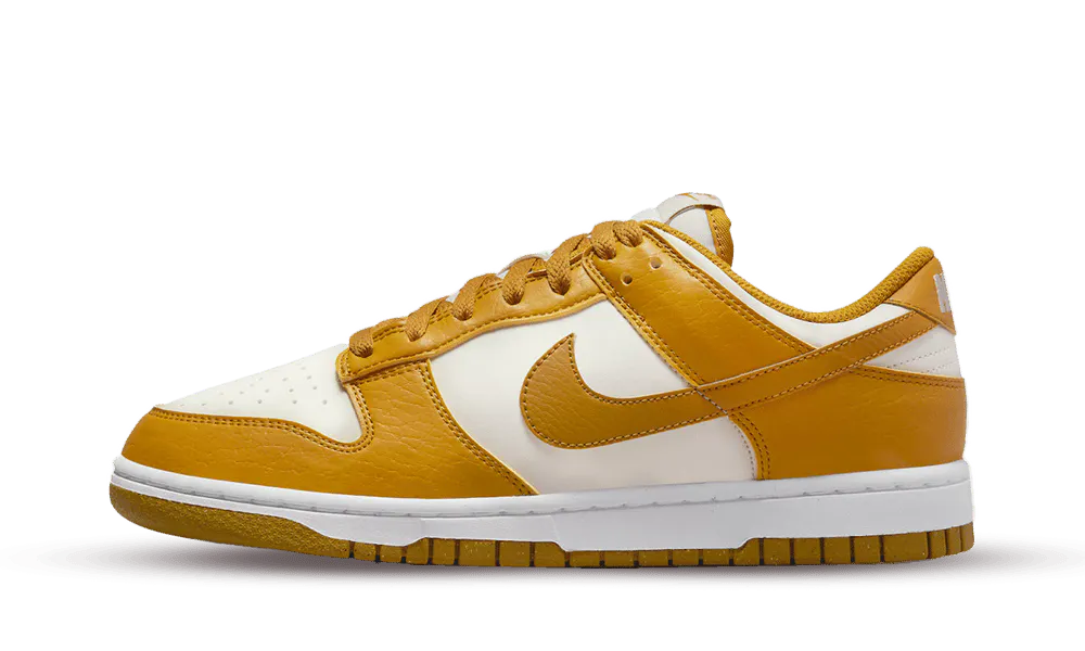 La Nike Dunk Low Next Nature Phantom presenta una classica base in pelle bianca liscia con sovrapposizioni in pelle giallo curry. La silhouette è realizzata con almeno il 20% di materiali riciclati, così come la suola Nike Grind. Nello stesso spirito, i marchi si abbinano al design con una tonalità gialla e bianca. Solo la soletta contrasta con il suo colore neon.