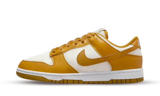 La Nike Dunk Low Next Nature Phantom presenta una classica base in pelle bianca liscia con sovrapposizioni in pelle giallo curry. La silhouette è realizzata con almeno il 20% di materiali riciclati, così come la suola Nike Grind. Nello stesso spirito, i marchi si abbinano al design con una tonalità gialla e bianca. Solo la soletta contrasta con il suo colore neon.