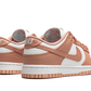 La Nike Dunk Low Rose Whisper presenta una tomaia in pelle bianca con sovrapposizioni di pelle rosa pesca. I lacci abbinati siedono su una lingua bianca che contrasta con i marchi come lo swoosh laterale. Una suola bianca con una suola rosa esalta il look retrò del design di Peter Moore.