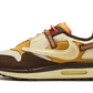 La Nike Air Max 1 Travis Scott Cactus Jack Baroque Brown presenta una base in mesh beige con inserti in pelle scamosciata marrone chiaro e scuro. Lo Swoosh invertito, che è diventato una firma della collaborazione tra Nike e Cactus Jack collaborazione, presenta una texture rettile in un beige angosciato. Ci sono tocchi colorati sul retro su una cinghia da arrampicata e sui lacci da trekking. Infine, un marchio Cactus Jack appare sul tallone e sulla linguetta.