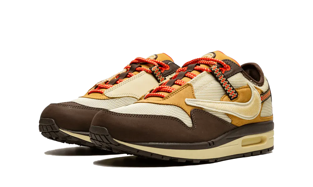 La Nike Air Max 1 Travis Scott Cactus Jack Baroque Brown presenta una base in mesh beige con inserti in pelle scamosciata marrone chiaro e scuro. Lo Swoosh invertito, che è diventato una firma della collaborazione tra Nike e Cactus Jack collaborazione, presenta una texture rettile in un beige angosciato. Ci sono tocchi colorati sul retro su una cinghia da arrampicata e sui lacci da trekking. Infine, un marchio Cactus Jack appare sul tallone e sulla linguetta.