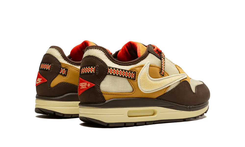 La Nike Air Max 1 Travis Scott Cactus Jack Baroque Brown presenta una base in mesh beige con inserti in pelle scamosciata marrone chiaro e scuro. Lo Swoosh invertito, che è diventato una firma della collaborazione tra Nike e Cactus Jack collaborazione, presenta una texture rettile in un beige angosciato. Ci sono tocchi colorati sul retro su una cinghia da arrampicata e sui lacci da trekking. Infine, un marchio Cactus Jack appare sul tallone e sulla linguetta.