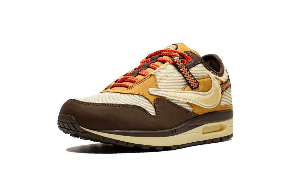 La Nike Air Max 1 Travis Scott Cactus Jack Baroque Brown presenta una base in mesh beige con inserti in pelle scamosciata marrone chiaro e scuro. Lo Swoosh invertito, che è diventato una firma della collaborazione tra Nike e Cactus Jack collaborazione, presenta una texture rettile in un beige angosciato. Ci sono tocchi colorati sul retro su una cinghia da arrampicata e sui lacci da trekking. Infine, un marchio Cactus Jack appare sul tallone e sulla linguetta.