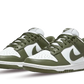 La Nike Dunk Low Medium Olive è caratterizzata da una base in pelle bianca liscia arricchita da sovrapposizioni in pelle verde oliva sul parafango, sugli occhielli, sul pannello laterale e sullo Swoosh. La coppia adotta un blocco di colori che rende il design molto efficace.