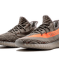 L'Adidas Yeezy Boost 350 V2 "Carbon Beluga" unisce vividi tocchi di colore con un design fantasia. I lacci in corda fissano la tomaia Primeknit traspirante, resa in una finitura grigio scuro con linee nere ondulate e macchioline arancioni a contrasto. Sul lato laterale, una striscia arancione abbinata mostra il marchio "SP