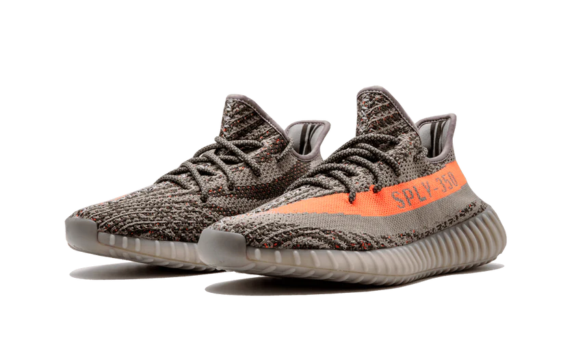 L'Adidas Yeezy Boost 350 V2 "Carbon Beluga" unisce vividi tocchi di colore con un design fantasia. I lacci in corda fissano la tomaia Primeknit traspirante, resa in una finitura grigio scuro con linee nere ondulate e macchioline arancioni a contrasto. Sul lato laterale, una striscia arancione abbinata mostra il marchio "SP