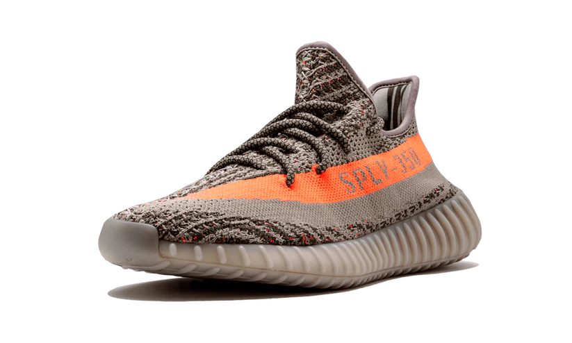 L'Adidas Yeezy Boost 350 V2 "Carbon Beluga" unisce vividi tocchi di colore con un design fantasia. I lacci in corda fissano la tomaia Primeknit traspirante, resa in una finitura grigio scuro con linee nere ondulate e macchioline arancioni a contrasto. Sul lato laterale, una striscia arancione abbinata mostra il marchio "SP